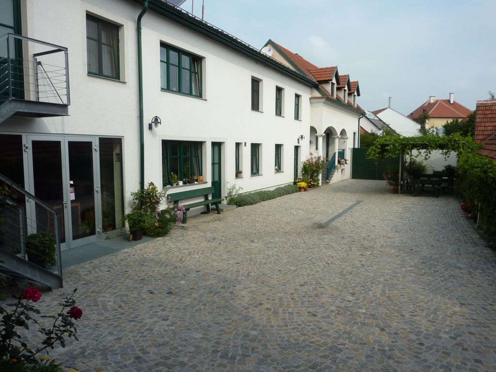 Inner courtyard of a winery with paved floor, white buildings and green window frames.