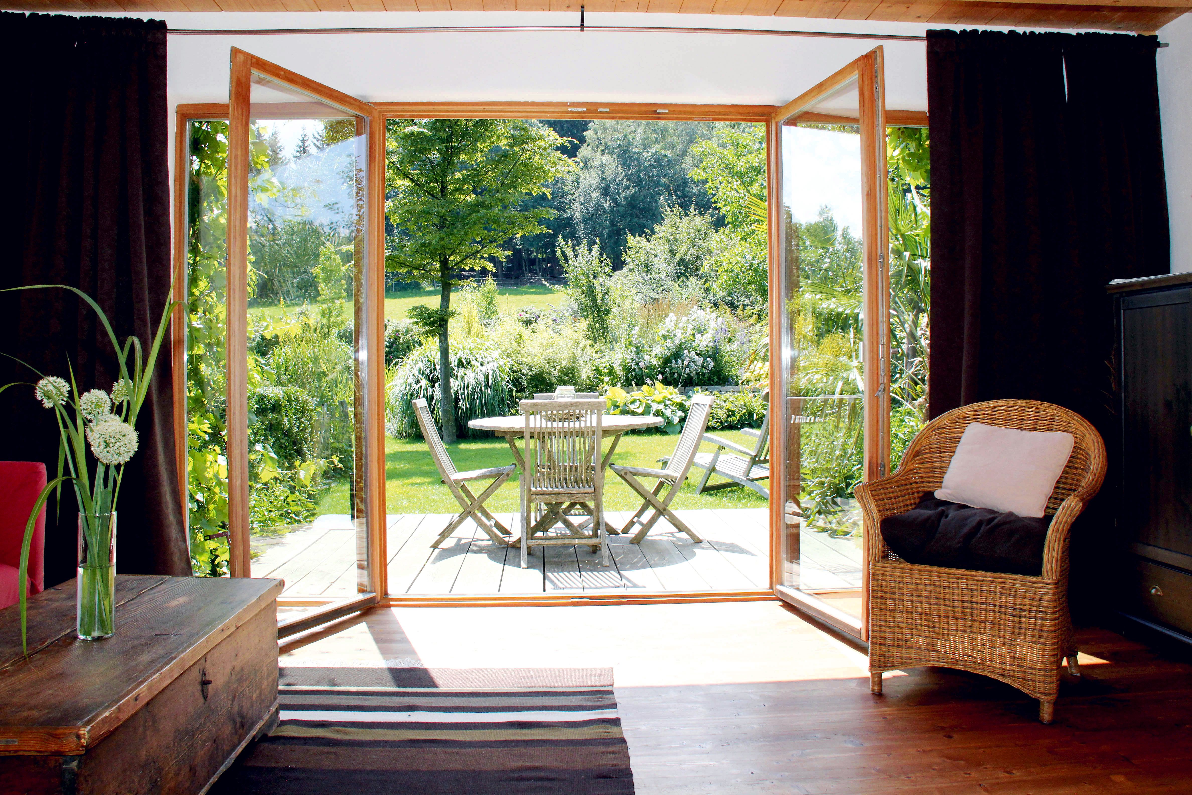 View from a living room onto a terrace with garden furniture and green garden.