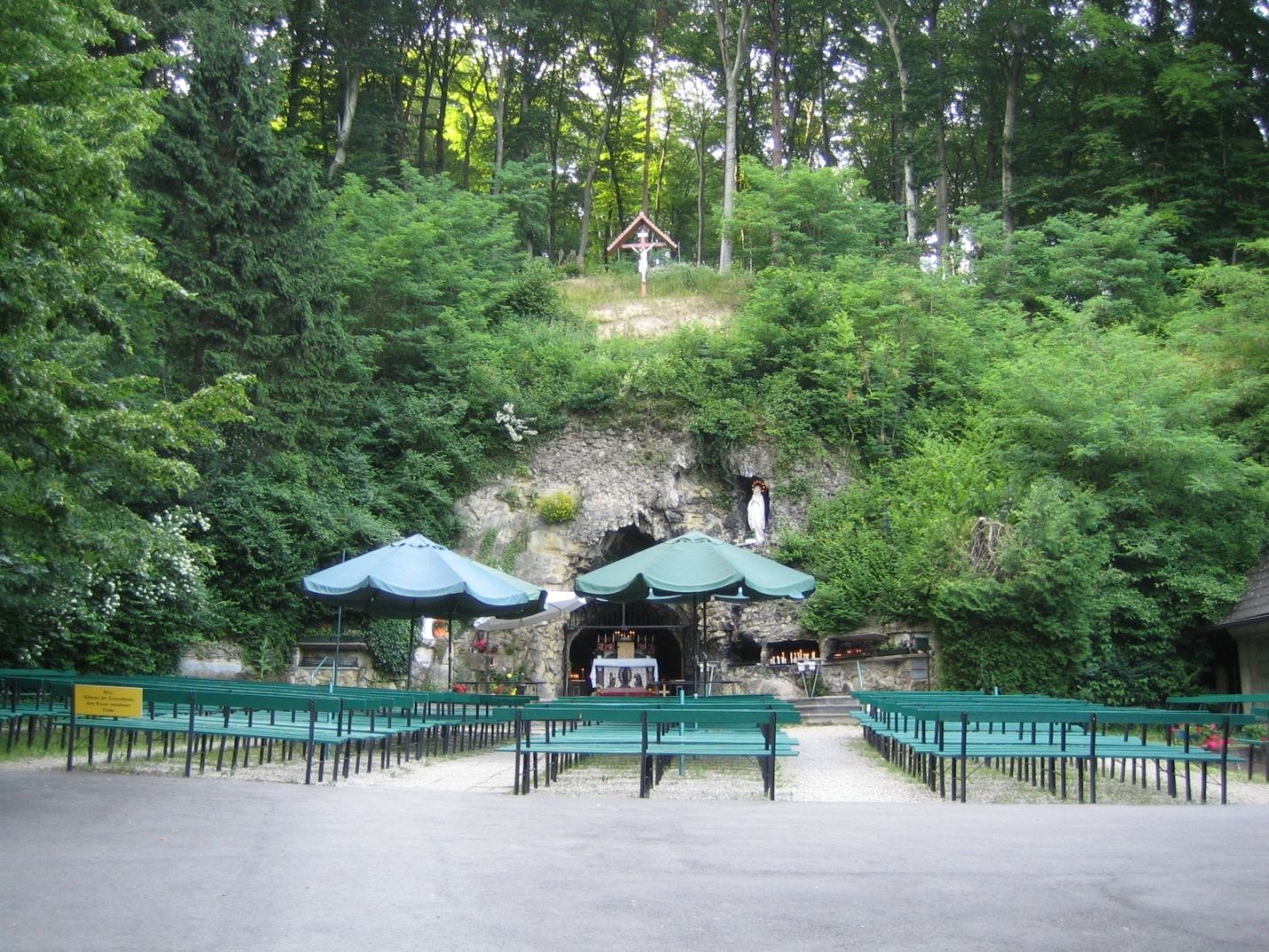 Lourdes grotto in the Vienna Woods with benches and green surroundings.