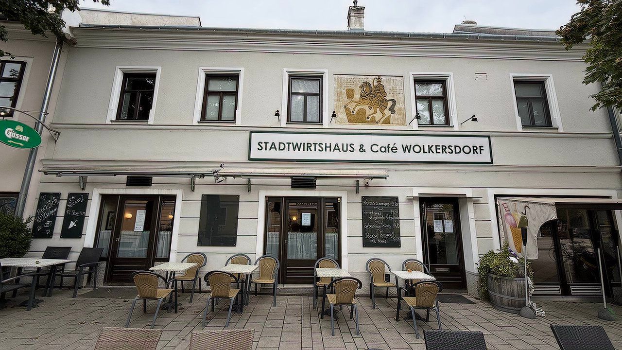 Exterior view of the Stadtwirtshaus & Café Wolkersdorf with tables and chairs on the terrace.
