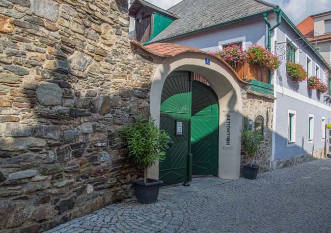 Historic building with green gate and flowers.