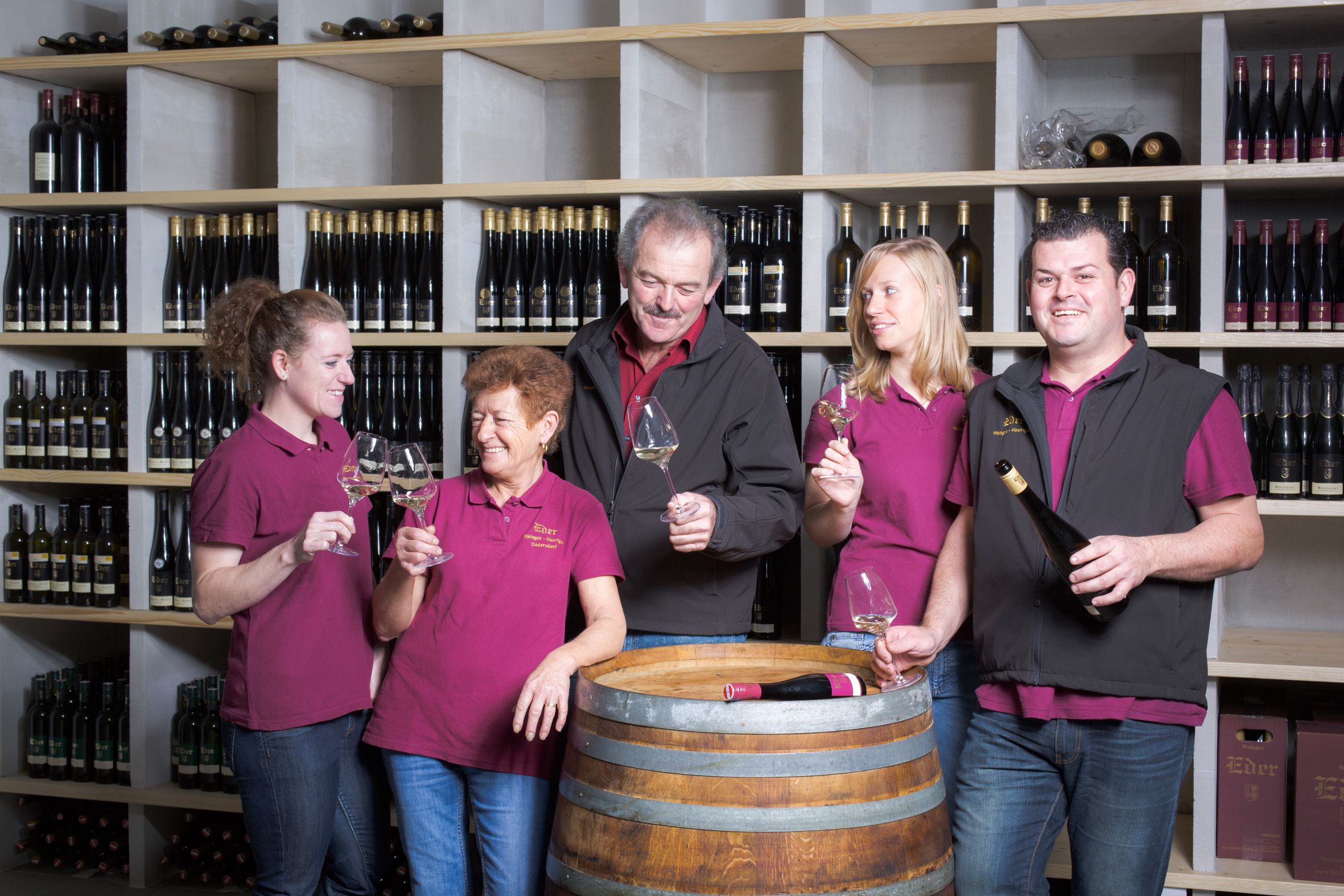 Five people in a wine cellar clink glasses.