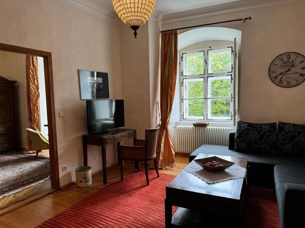 Cozy guest room with sofa, table, TV and large window.