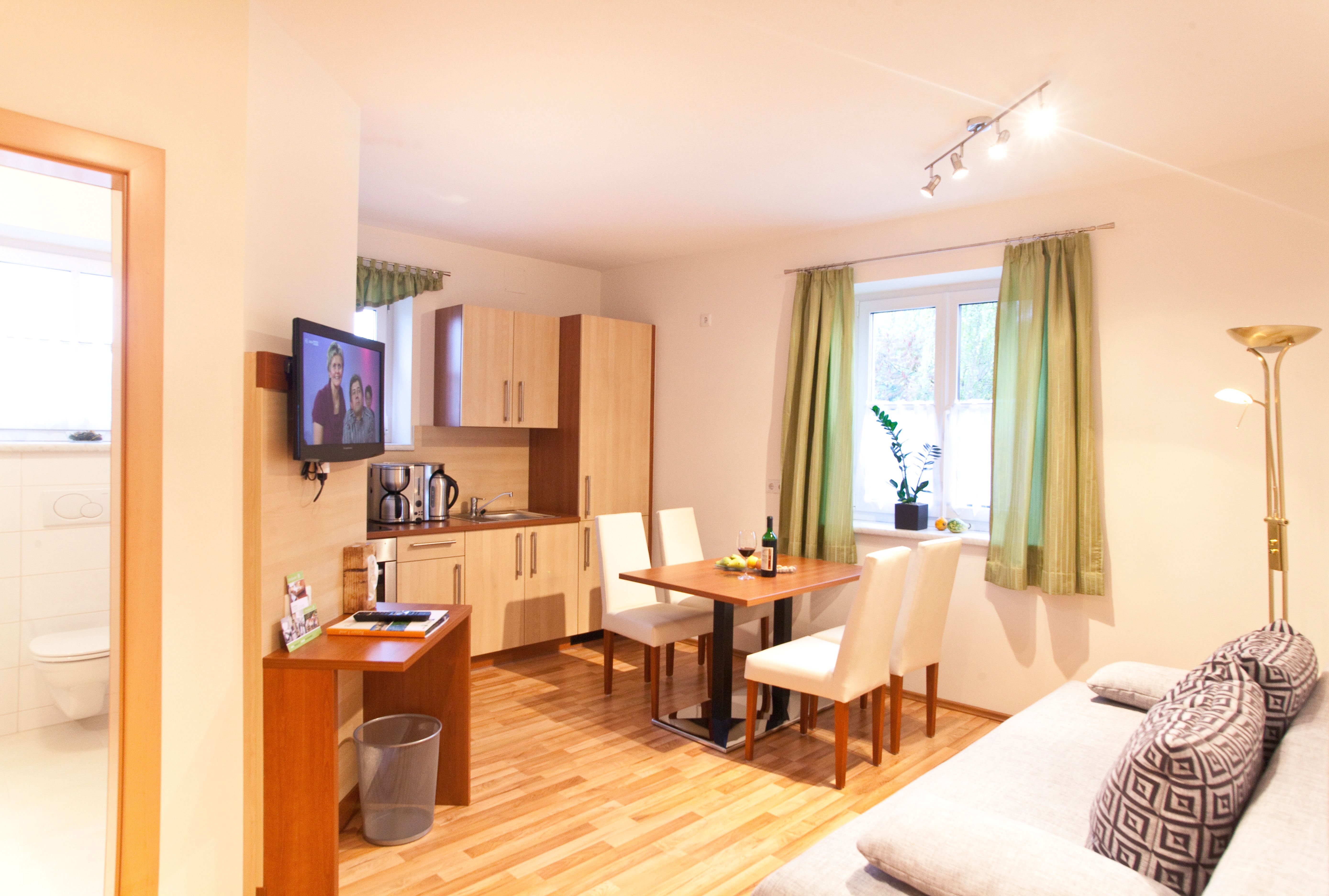 Modern kitchen with dining table, sofa and TV in a bright room.