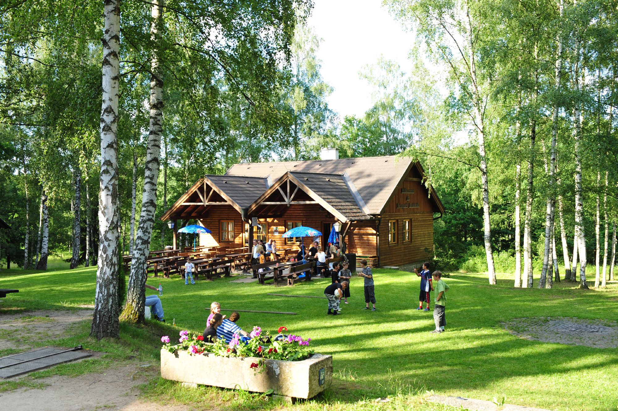 Wooden hut in the Blockheide nature park with children playing and trees.