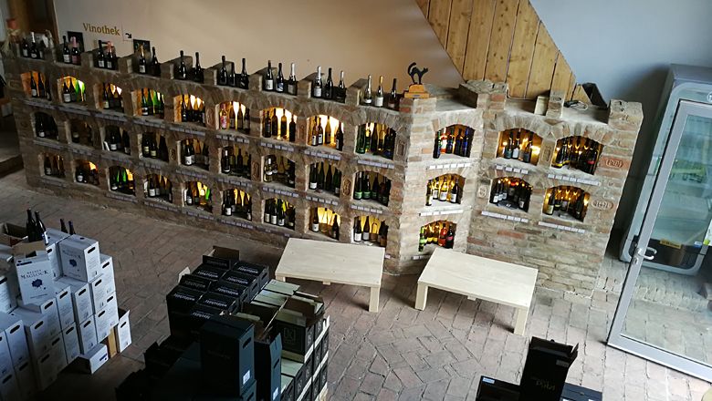 Interior view of a wine shop with wine bottles on brick shelves.