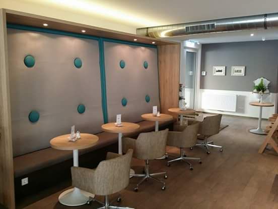 Interior view of a modern café with upholstered walls, round tables and comfortable chairs.