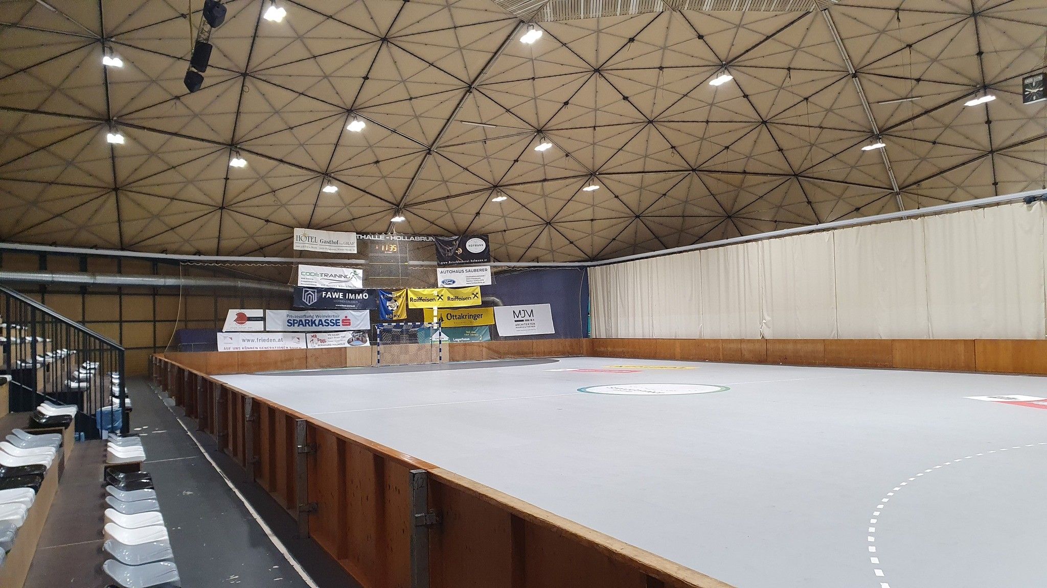 Interior view of the Hollabrunn sports hall with empty stands and playing field.
