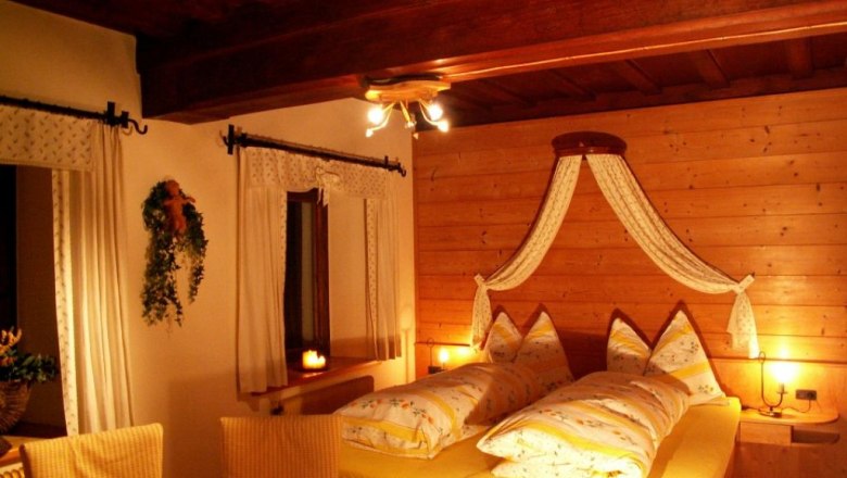Cozy bedroom with wooden walls and yellow bed linen.