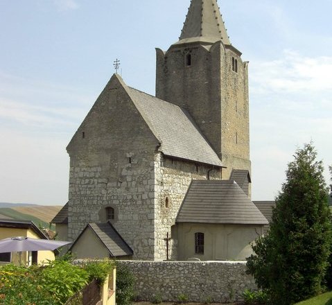 Historic fortified church with stone tower and pointed roof.