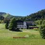 A sports hotel in a green mountain landscape with a blue sky.