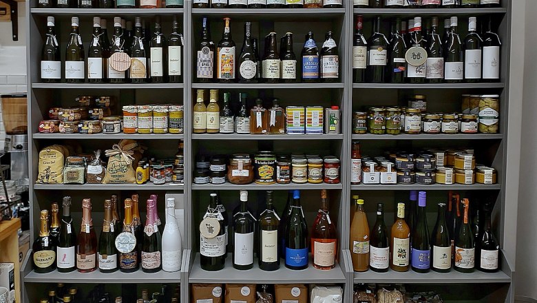 Shelves with wine bottles, glasses and food.