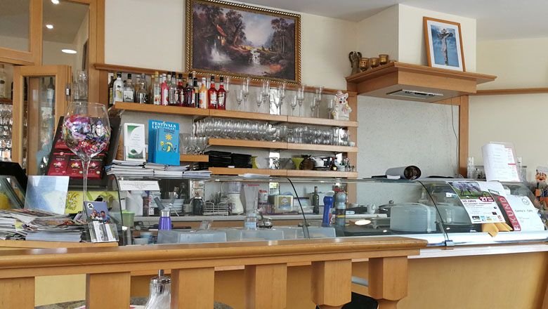 Interior view of a café with counter, glasses and decorations.
