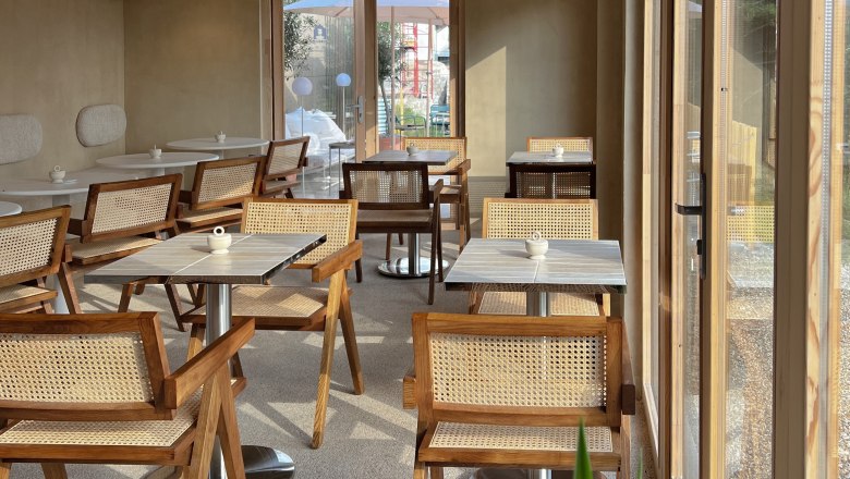 Interior of a caf&eacute; with wooden furniture and large windows.