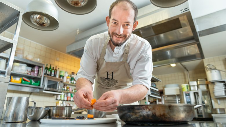A chef in a professional kitchen prepares a dish.