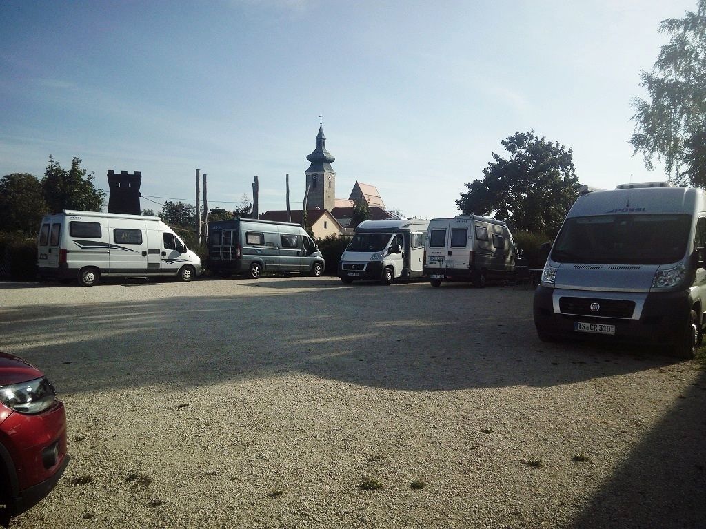 Motorhome site with several parked motorhomes and a church in the background.
