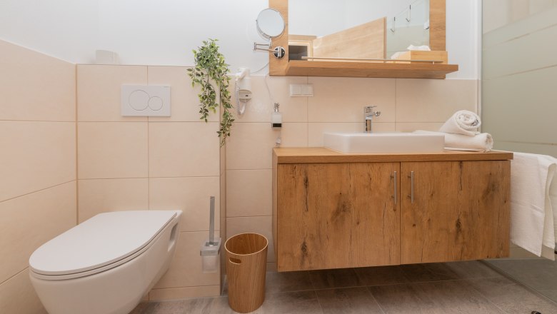 Modern bathroom with wooden washbasin, sink, toilet and towels.