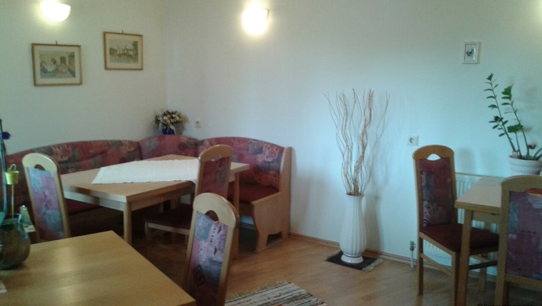 Cozy seating area in a communal kitchen with wooden tables and upholstered chairs.