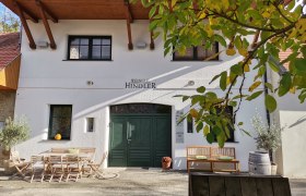 Entrance to a winery with wooden furniture and plants.