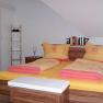 Cozy bedroom with double bed and yellow-red bed linen.