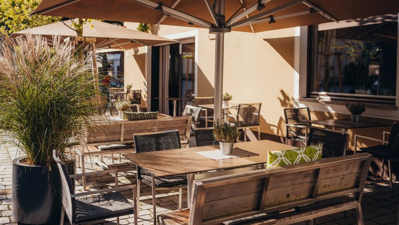 Sunny outdoor area of a café with tables, chairs and parasols.