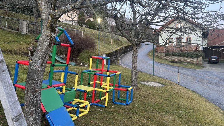 Colorful climbing frames on a meadow next to a road in a rural area.