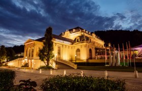 Illuminated Casino Baden at night with a dramatic sky.