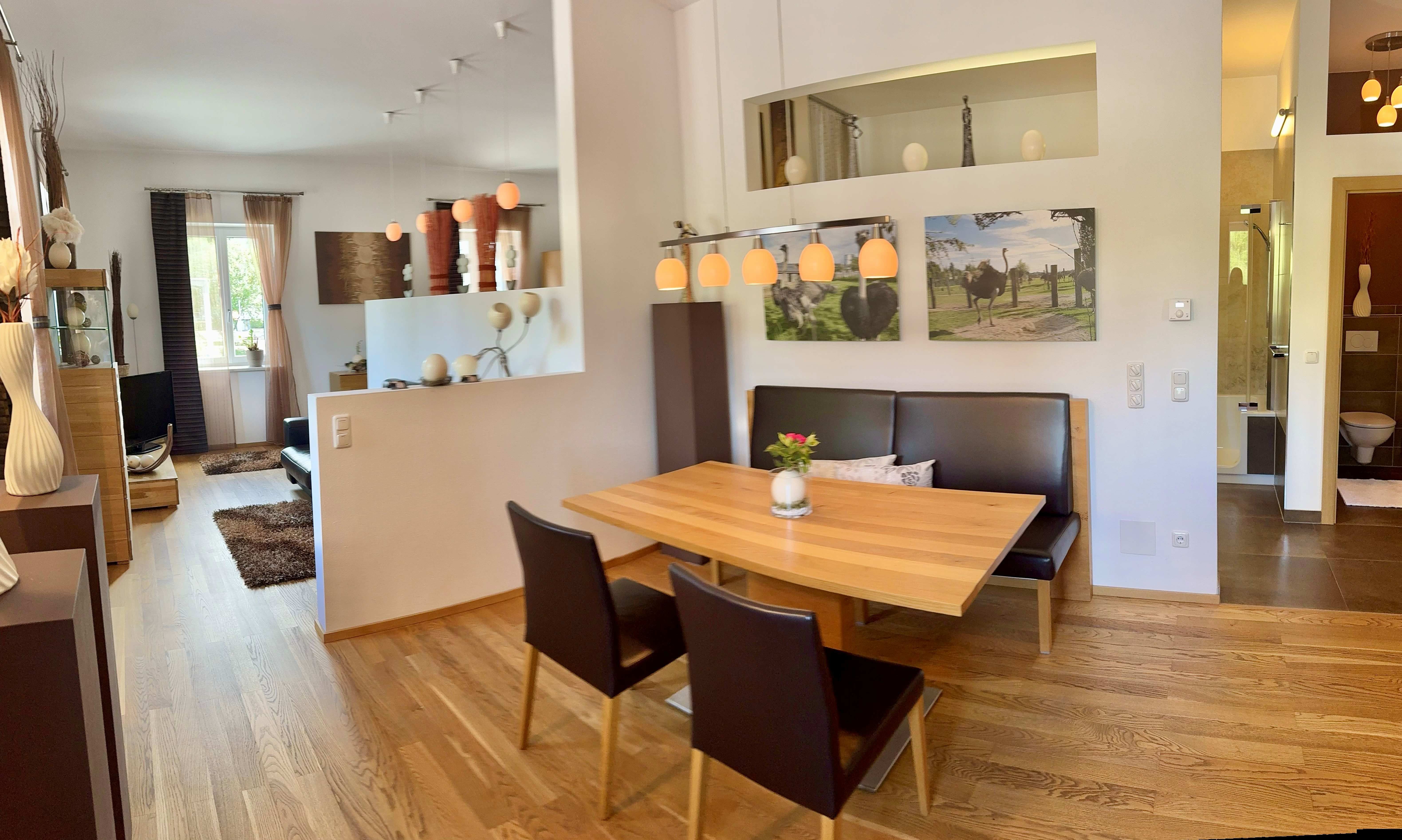A modern living room furnished with a dining table, chairs, and decorations, including pictures of ostriches.