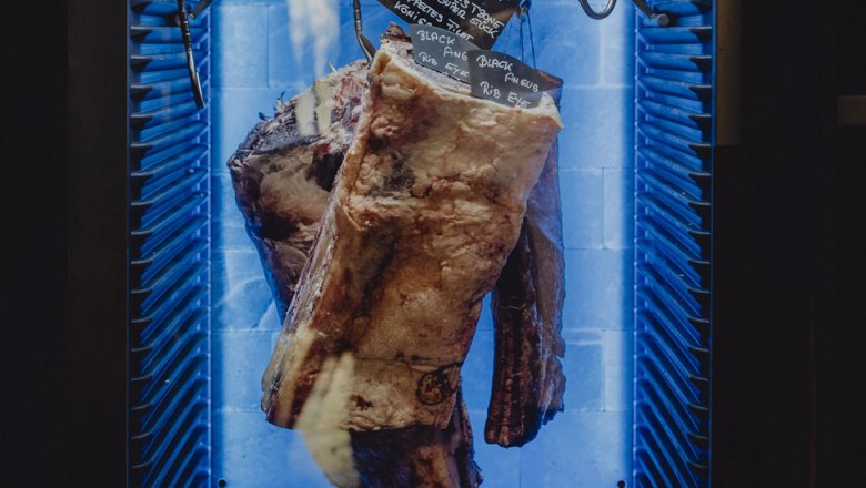 Large piece of meat in a maturing cabinet with blue lighting.