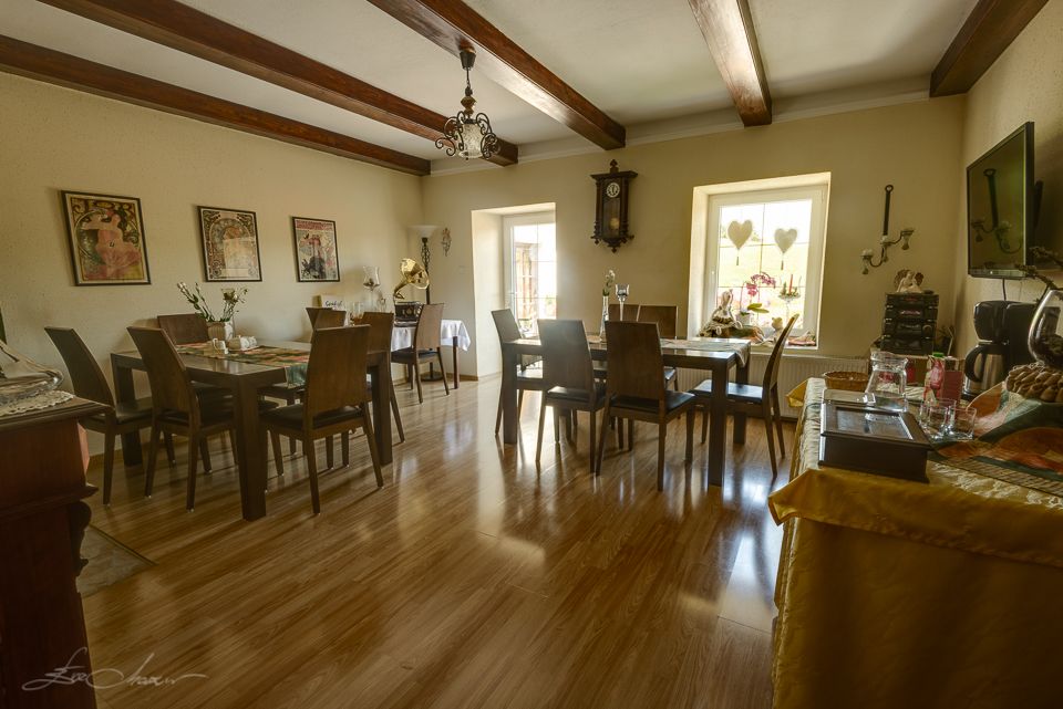 Cozy breakfast room with wooden floor, tables and chairs, decorated with pictures and a wall clock.