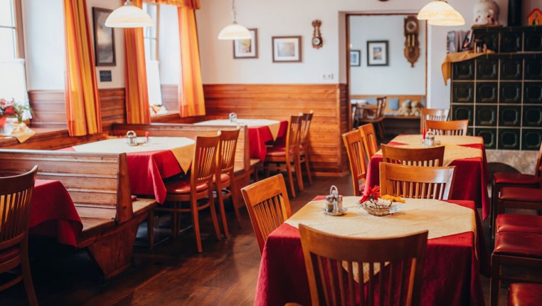 Cozy dining room with wooden furniture, red tablecloths and yellow curtains, in the style of the 1940s.