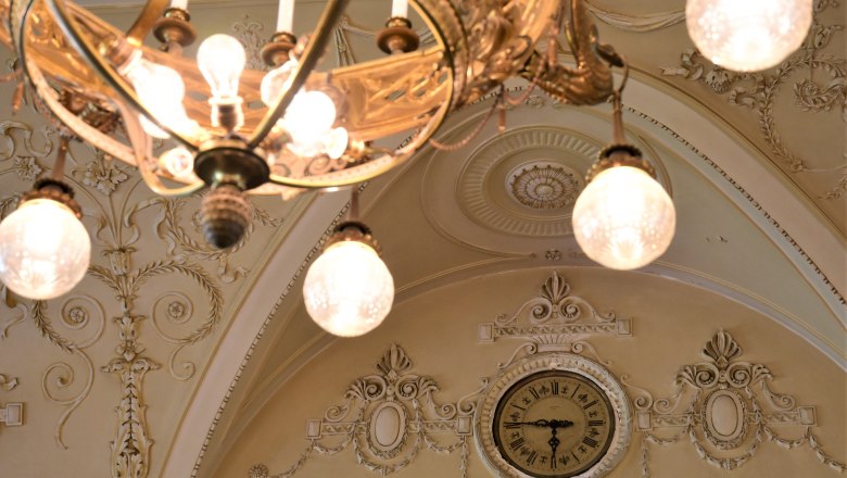 Close-up of a decorative ceiling with chandelier and clock in the Südbahnhotel.