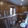 Bathroom with brown tiles, shower, washbasin, toilet and washing machine.