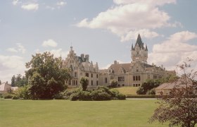 Grafenegg Castle with extensive lawn and trees in the foreground.