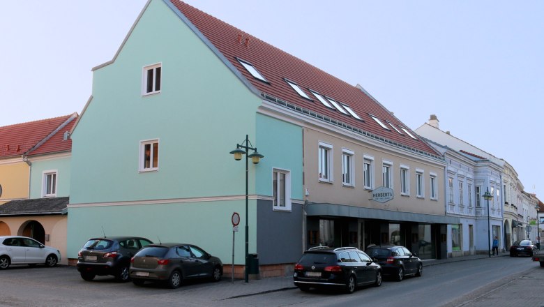 Street scene in Traismauer with multi-storey building and parked cars.
