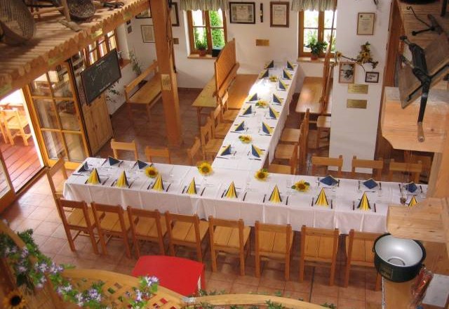 Interior view of an inn with set tables and wooden chairs.