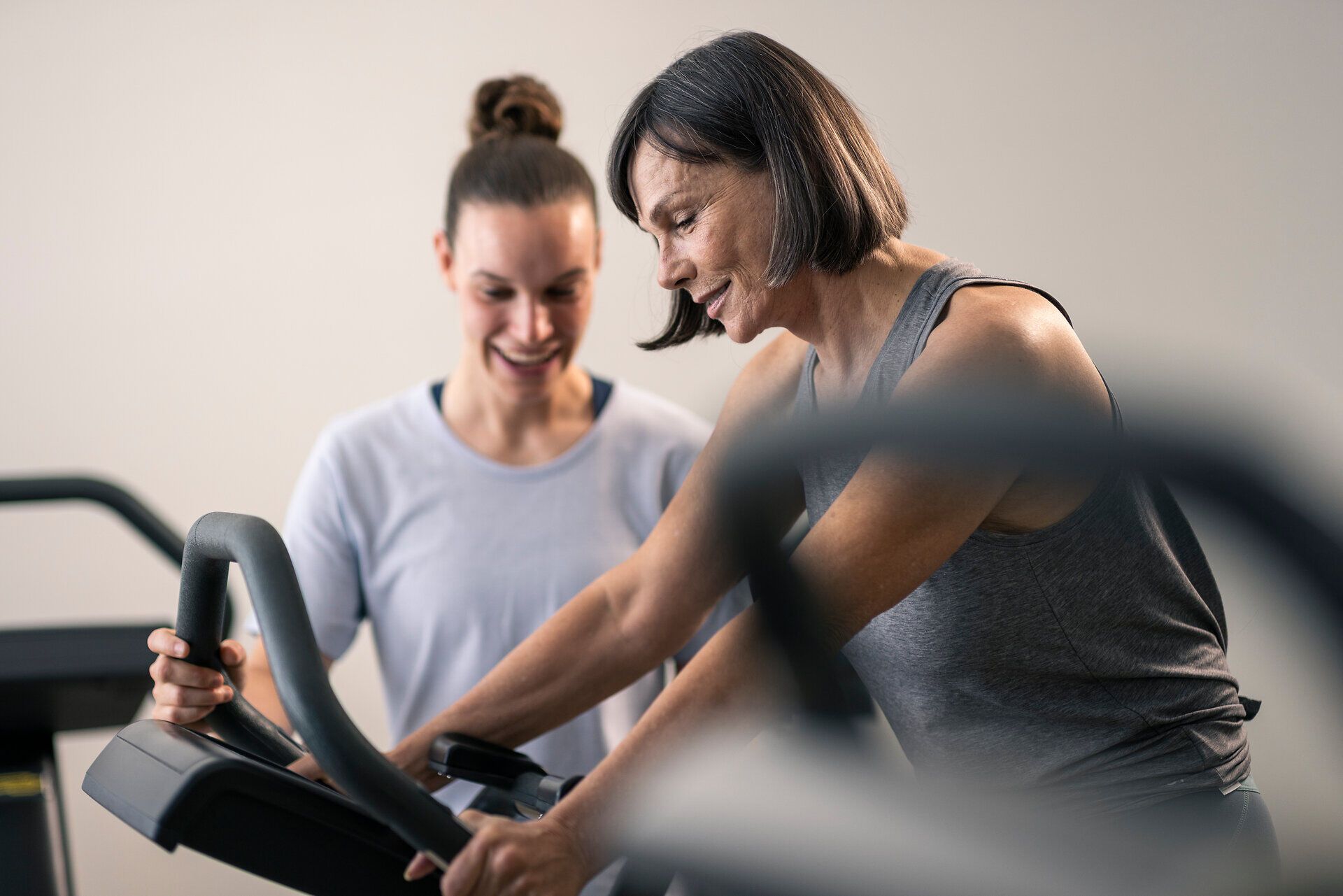 A therapist is assisting a woman as she works out on an ergometer at the Moorheilbad Harbach Health and Rehabilitation Center in the Waldviertel region. Both appear focused and friendly.