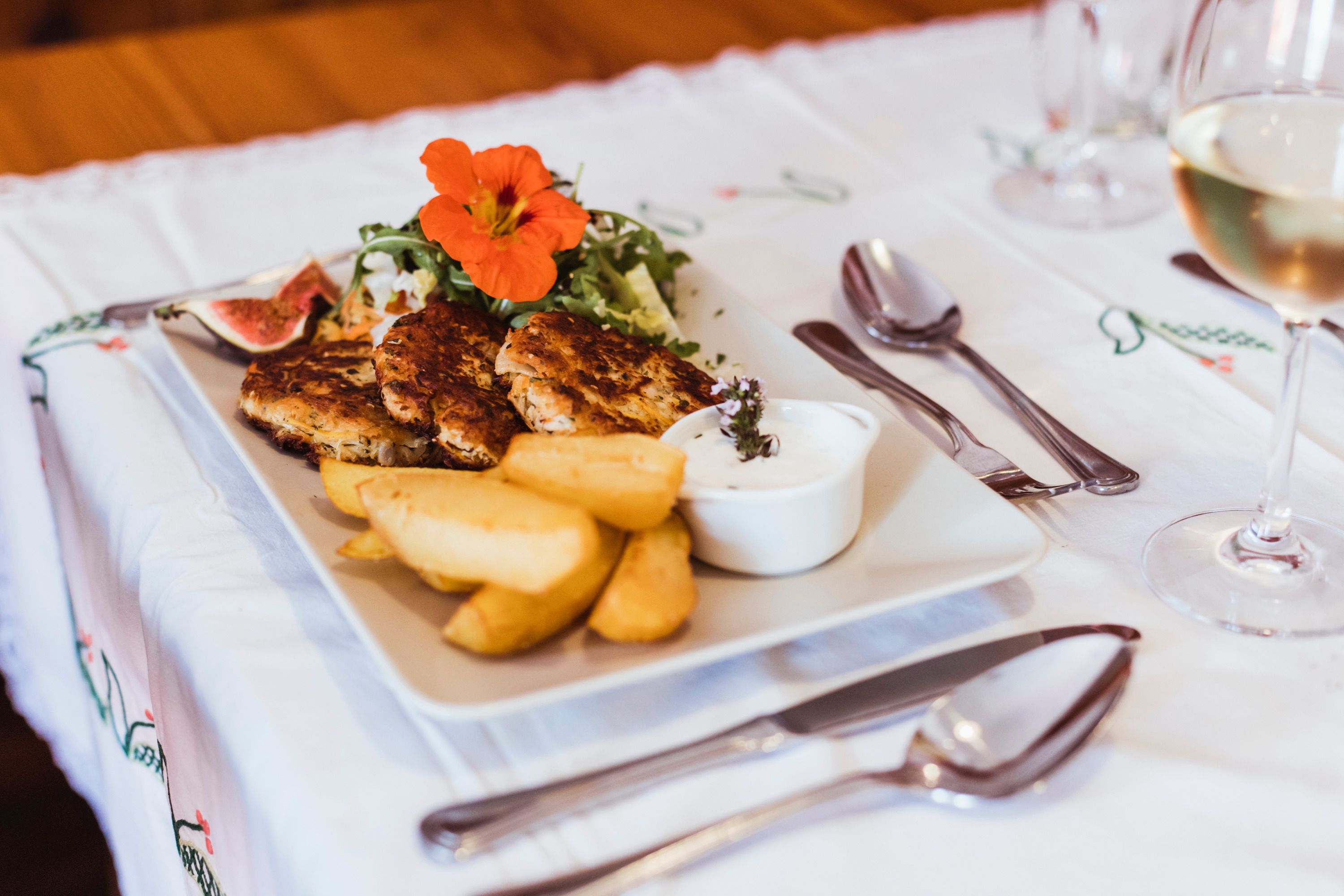 A plate of wholemeal sauerkraut loafs, potato wedges, salad and dip on a table.