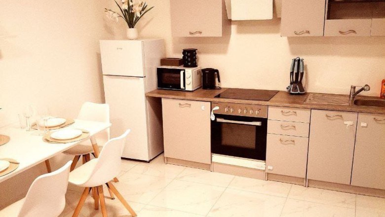 Modern kitchen with dining table, fridge, stove and microwave.