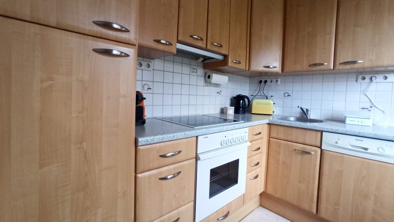 Kitchen with wooden cupboards, stove, sink and worktop.