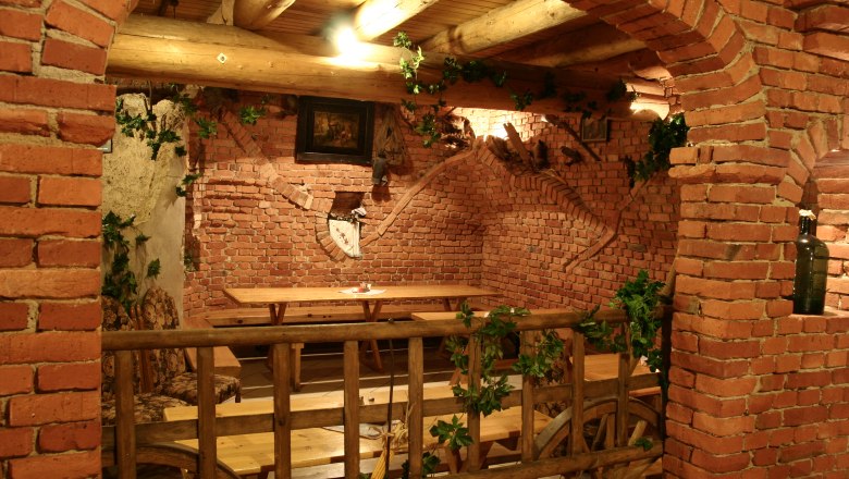 Rustic room with brick walls, wooden tables and decorations made from grapevines.