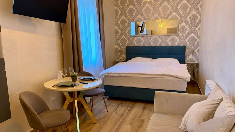 A cozy hotel room with double bed, small dining table and sofa.