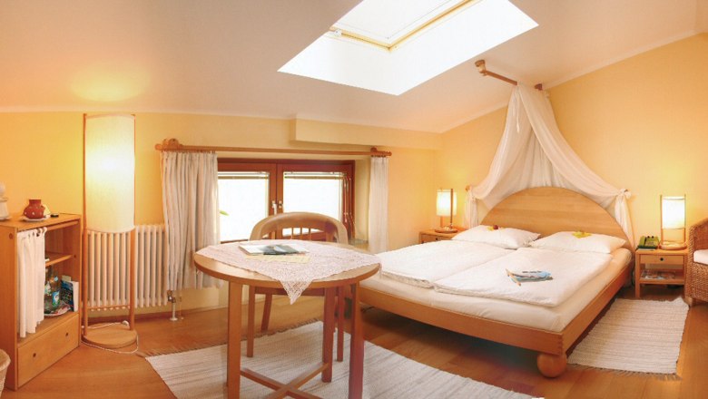Comfortable hotel room with double bed, table and skylight.