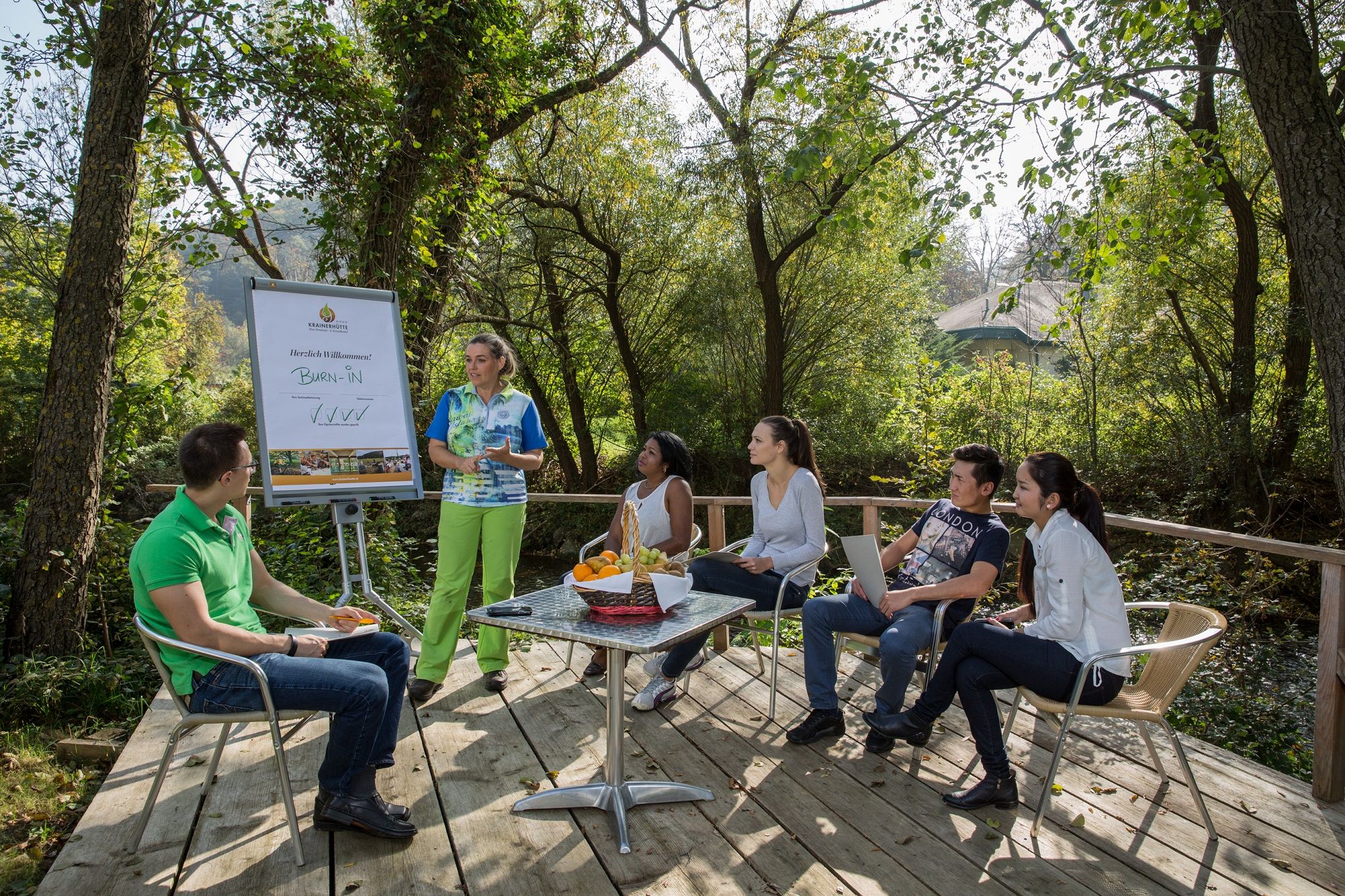 Group of people at an outdoor meeting in a wooded area.