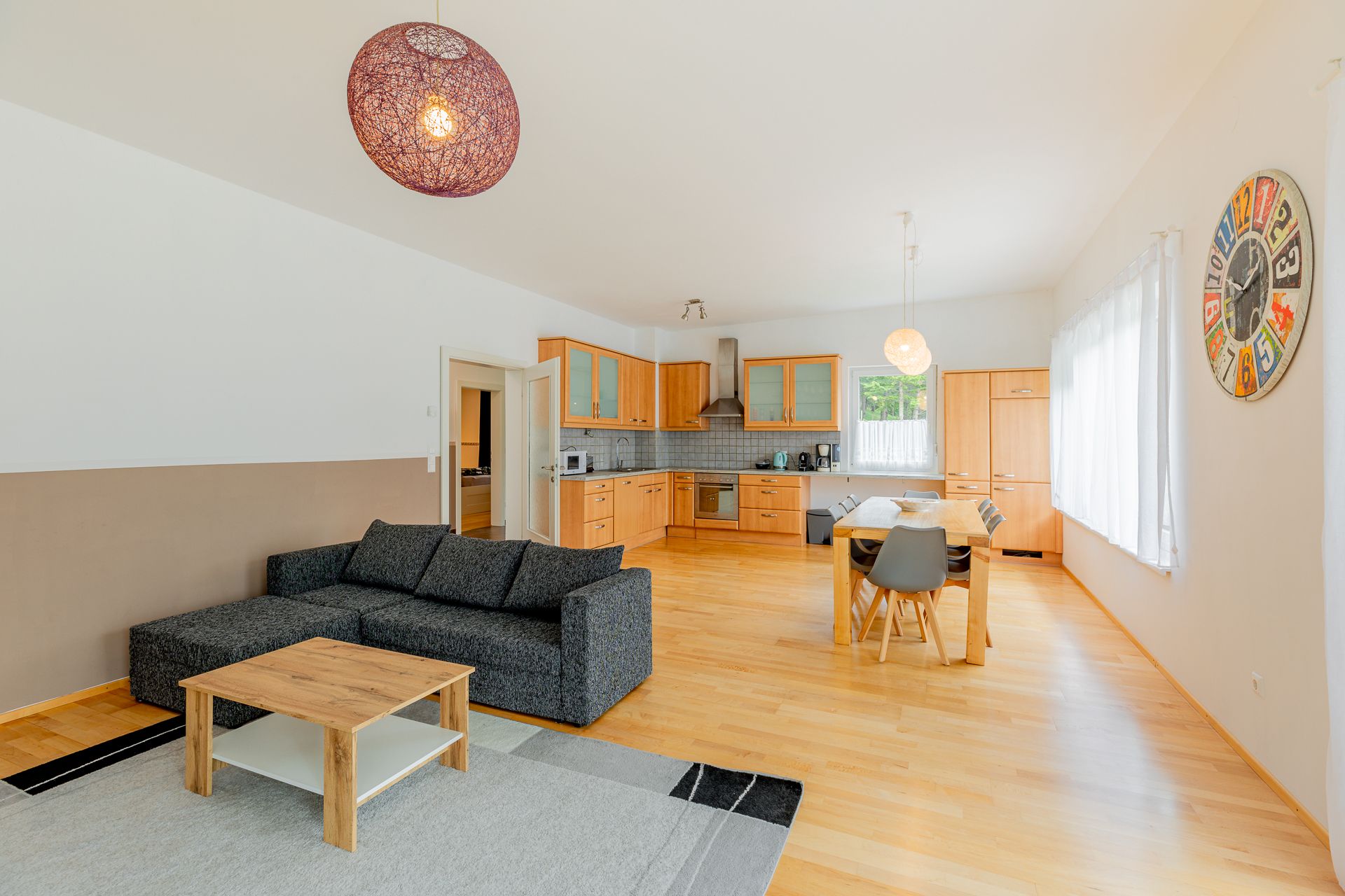 Open living area with kitchen, dining table and sofa.