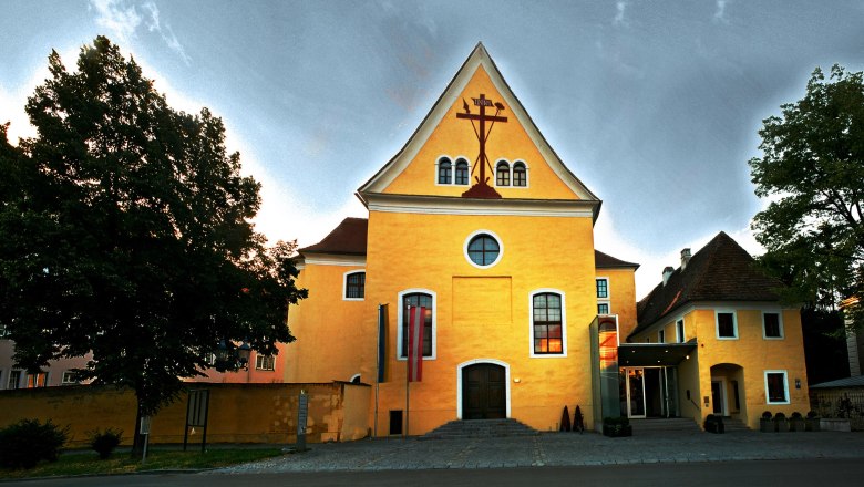 Yellow building with cross symbol and flags in front of the entrance.