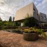 Modern wooden garden lofts with pond and plants in the foreground.