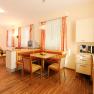 Bright room with wooden floor, dining table, kitchen and bed.