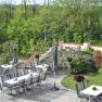 Guest terrace with tables, chairs and parasols, surrounded by green vegetation.