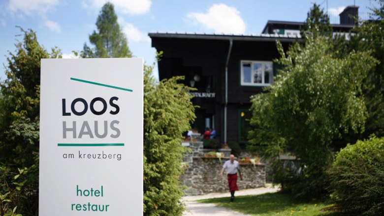 Entrance to the Looshaus am Kreuzberg with sign and garden.